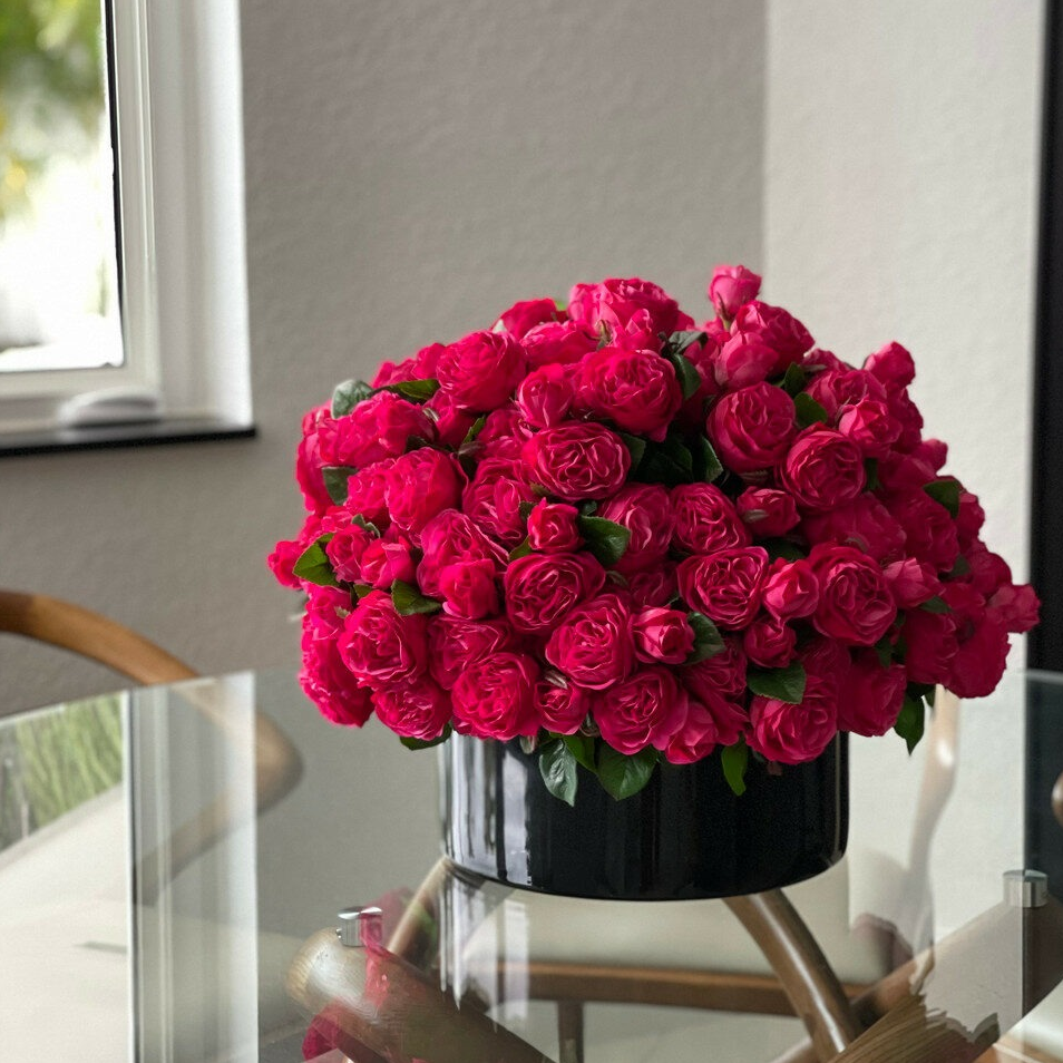 oscuro rosa inglés rosas en un negro vidrio jarrón.