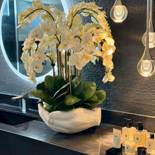 blanco phalaenopsis orquídeas en un abiertas manos escultórico jarrón