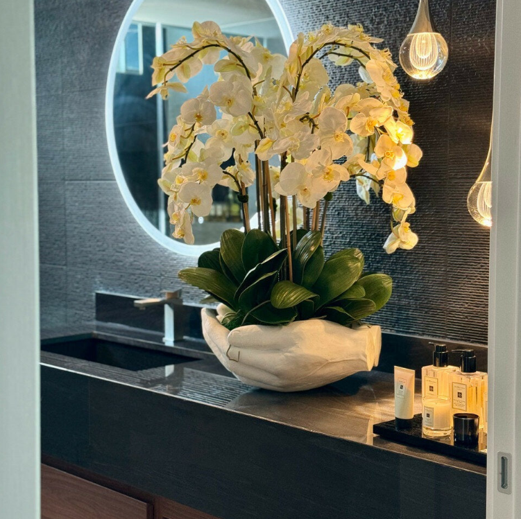 blanco phalaenopsis orquídeas en un abiertas manos escultórico jarrón